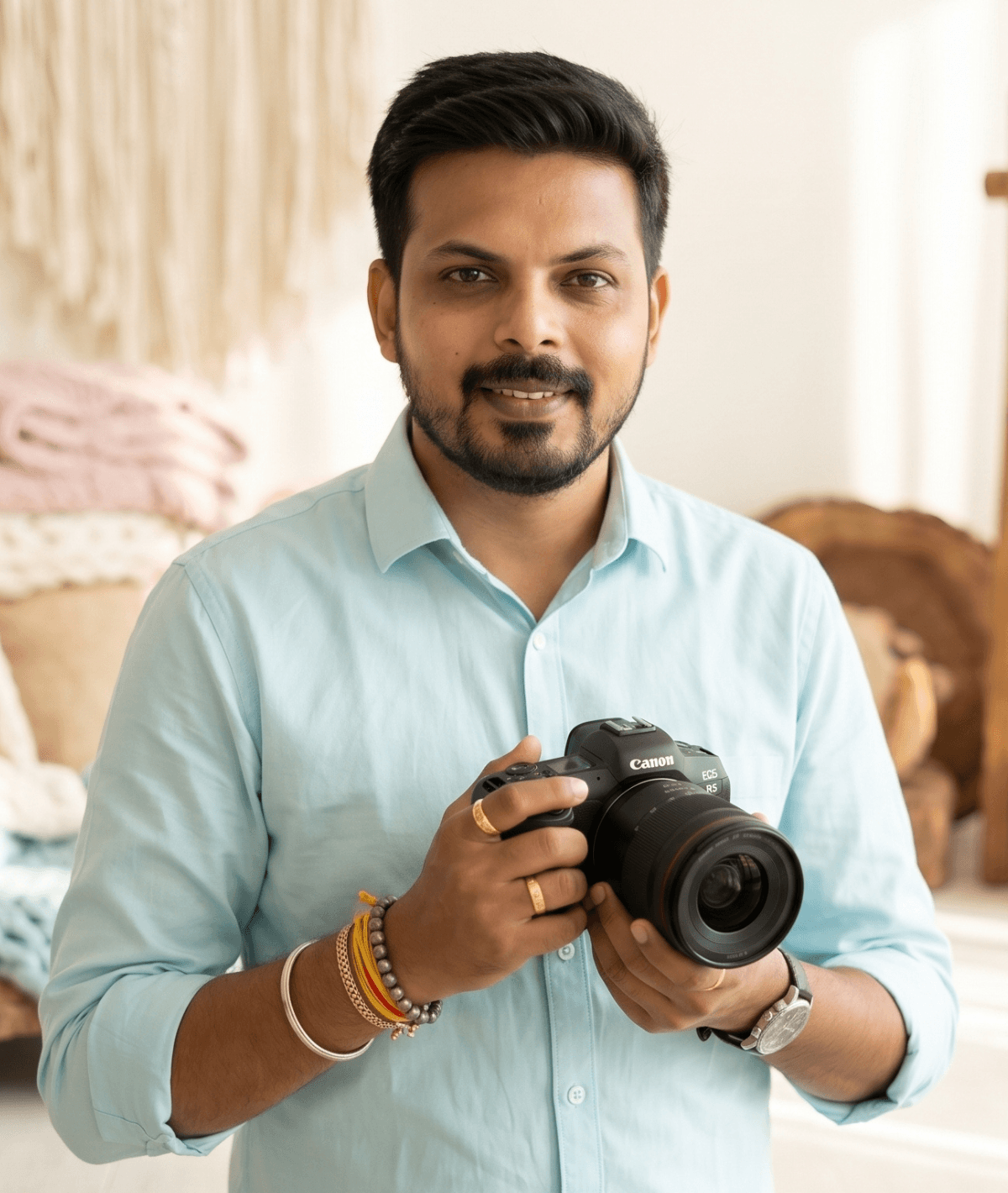 Paritosh Pandit holding a camera inside a pastel newborn photography studio